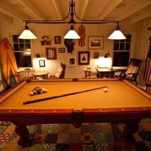 Game Room Image with Betsy Ross flag, pool table, white painted walls, nice looking furnitures and decors at night