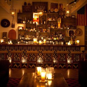 Main Bar Image with dimly lit lounge, scented candles in glass, bar stools and wide variety of liquor displayed